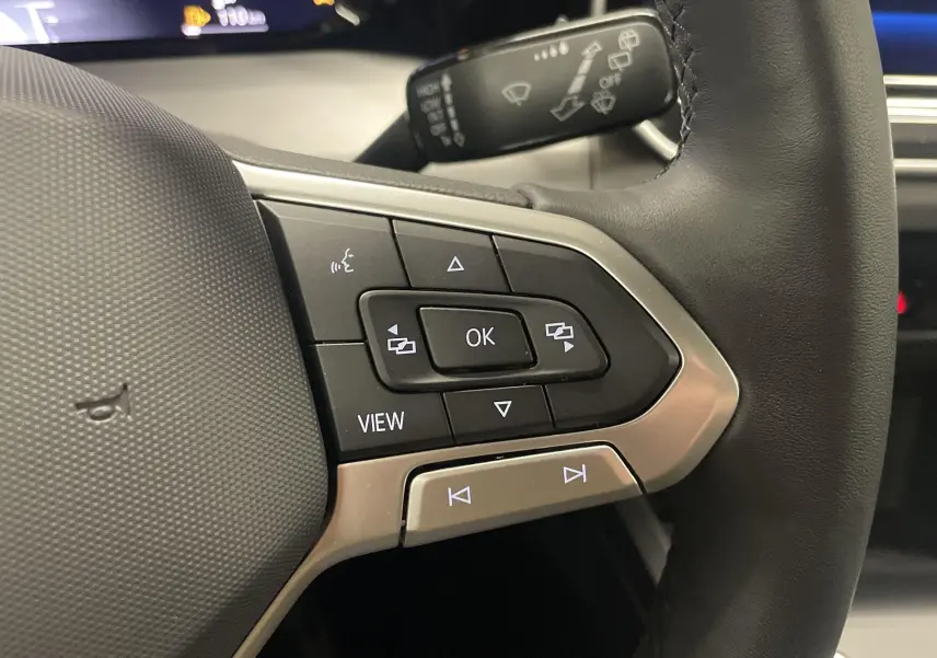 Gros plan sur les commandes multifonctions à droite du volant noir d'une Volkswagen Golf 1.5 TSI 2024.