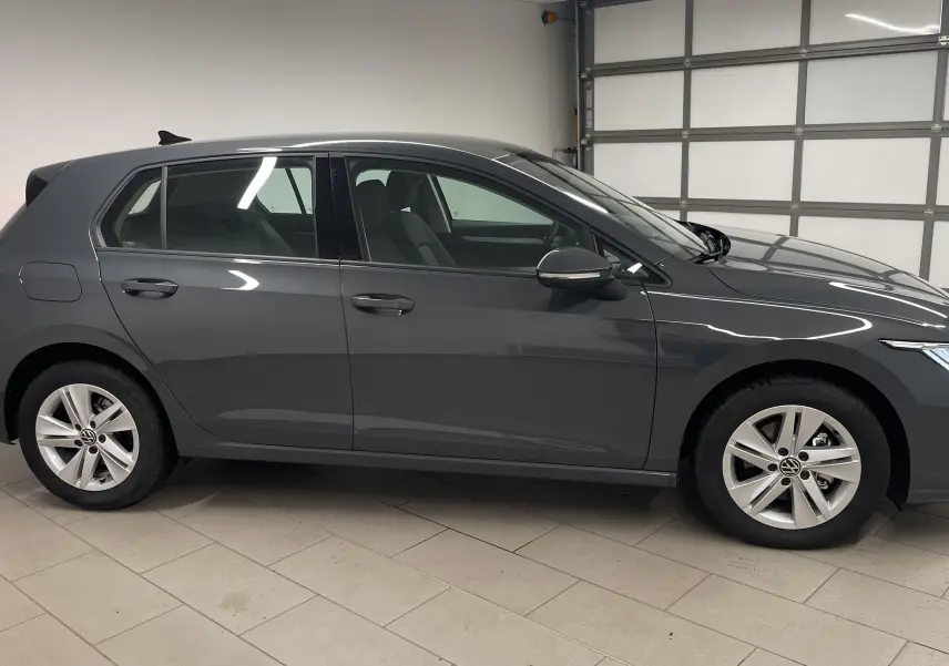 Profil droit d'une Volkswagen Golf 1.5 TSI 116 BVM6 VW Edition 2024 en gris dauphin métallisé dans un garage.