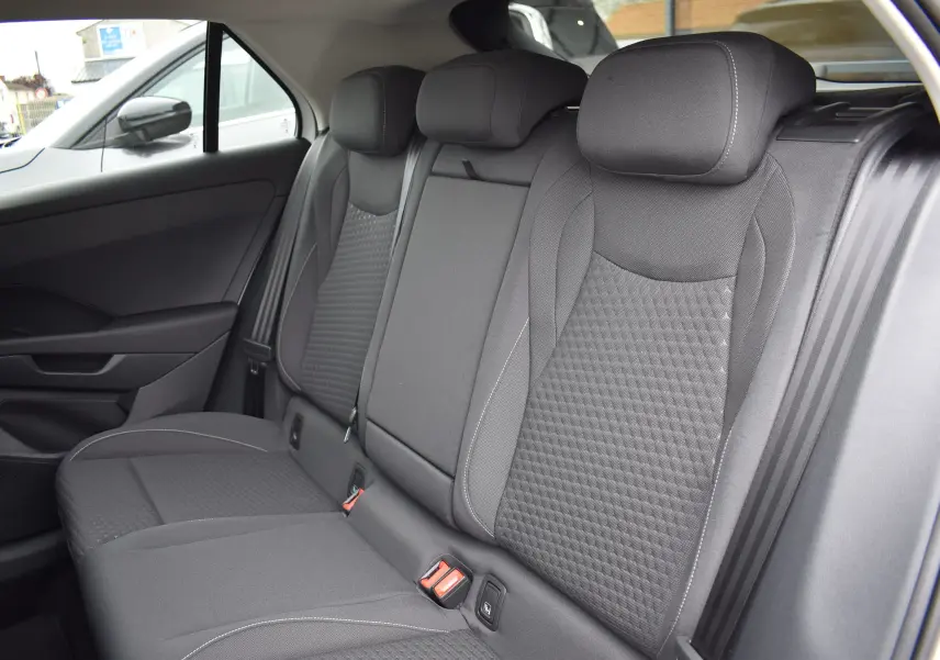 Vue intérieure sur la banquette arrière en tissu gris foncé du Volkswagen T-Roc 2025, avec appuie-têtes et ceintures visibles.