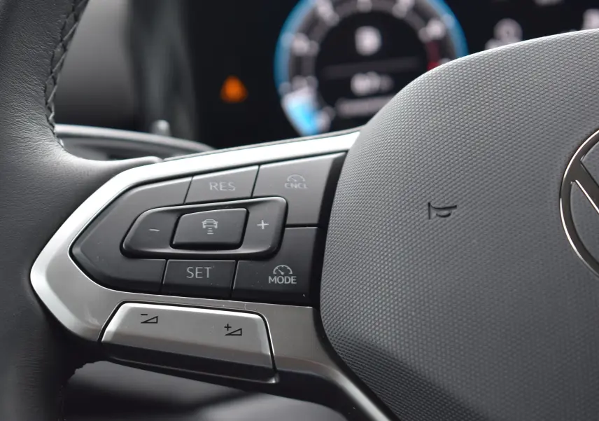 Gros plan sur les commandes multifonctions à gauche du volant du Volkswagen T-Roc blanc 2025.