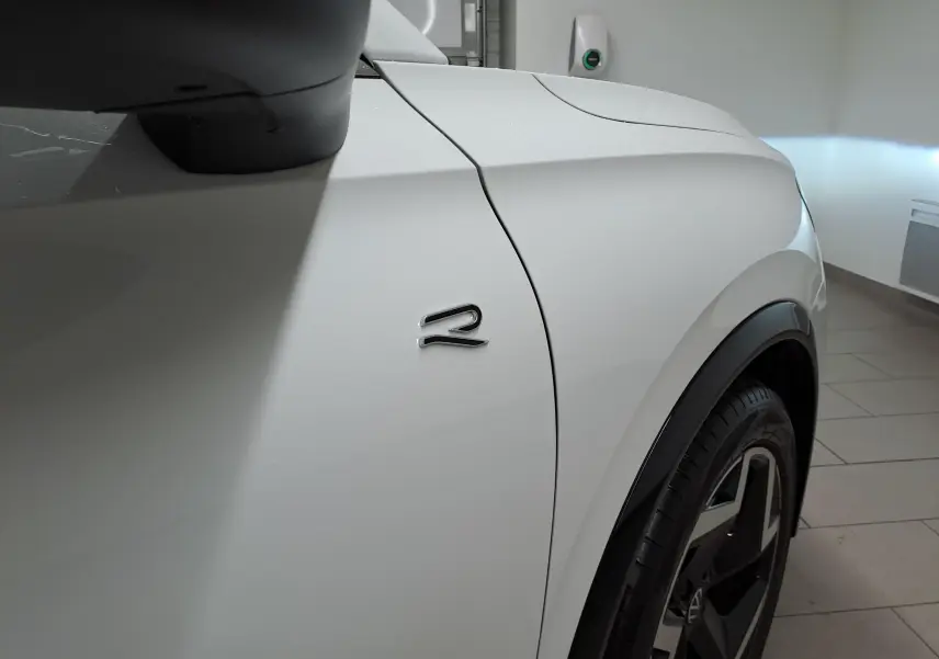 Détail de l'aile avant côté gauche du Volkswagen Tiguan blanc pur avec logo R distinctif et jante noire.