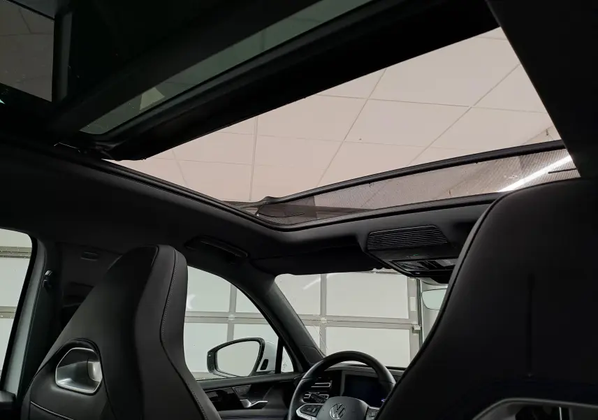 Vue intérieure du Volkswagen Tiguan 2025 R-Line Edition montrant le toit ouvrant panoramique et les sièges avant noirs.
