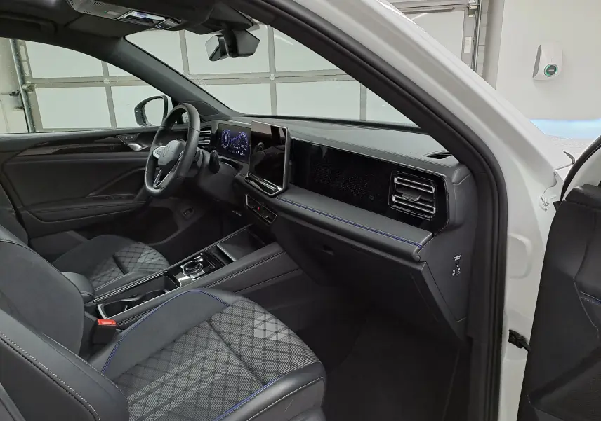 Intérieur du Volkswagen Tiguan 2025 blanc pur, vue côté passager, tableau de bord moderne avec écran tactile central.