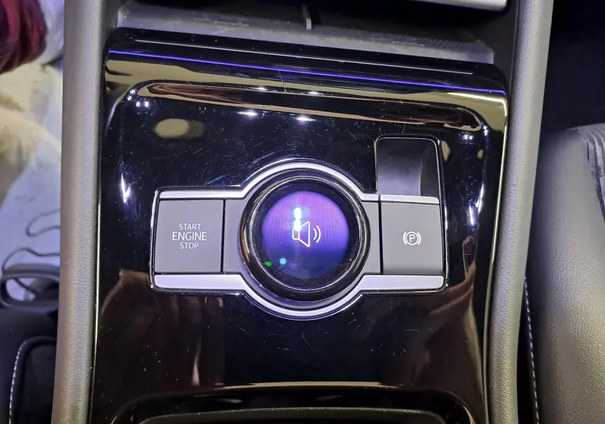 Gros plan sur la console centrale noire brillante du Volkswagen Tiguan 2025 avec bouton start/stop et frein à main électronique.