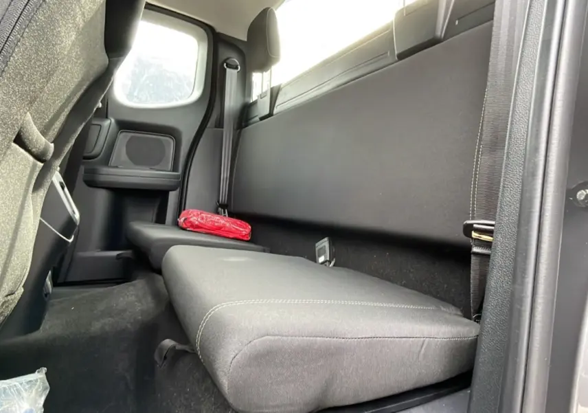 Vue intérieure arrière côté droit du Ford Ranger gris carbone, banquette simple avec ceinture et trousse de secours rouge.
