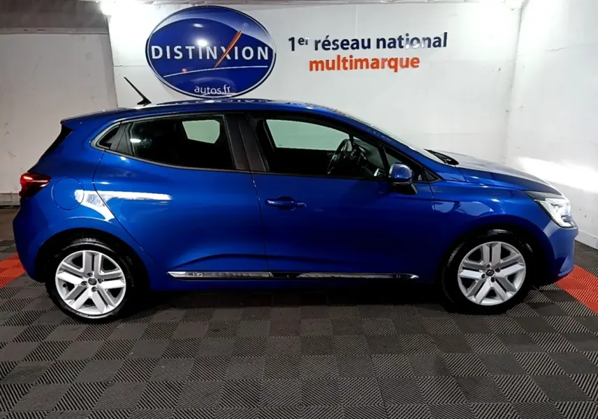Vue latérale droite d'une Renault Clio Business bleu métallisé, stationnée en intérieur avec jantes alliage visibles.