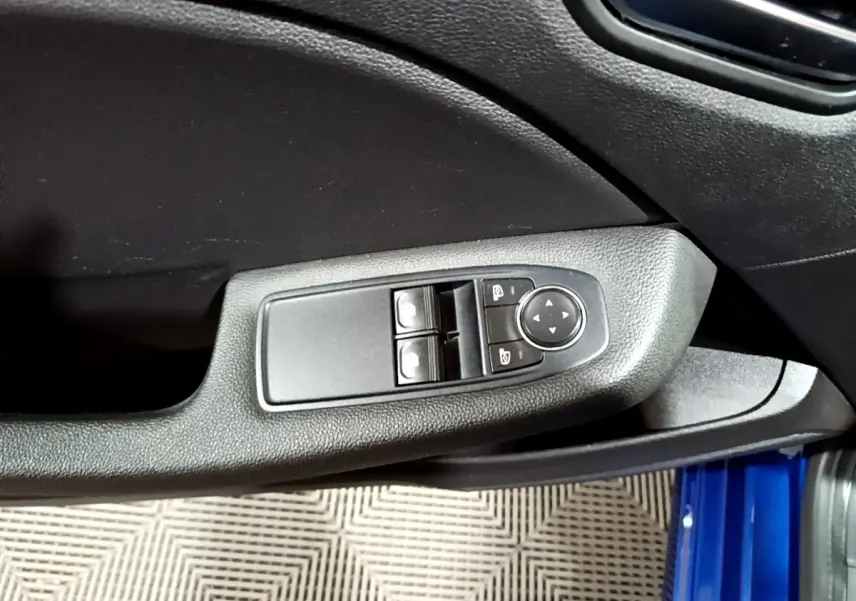 Vue rapprochée de la commande des vitres et rétroviseurs sur la porte côté conducteur d’une Renault Clio bleu 2022.