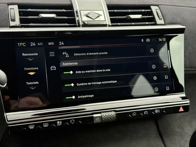 Écran tactile central du DS7 E-TENSE 2024 montrant les aides à la conduite, avec finition intérieure noire et détails chromés.
