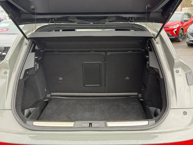 Coffre ouvert vu de l'arrière d'un DS7 E-TENSE gris 2024, montrant l'espace de chargement vide et la finition intérieure noire.