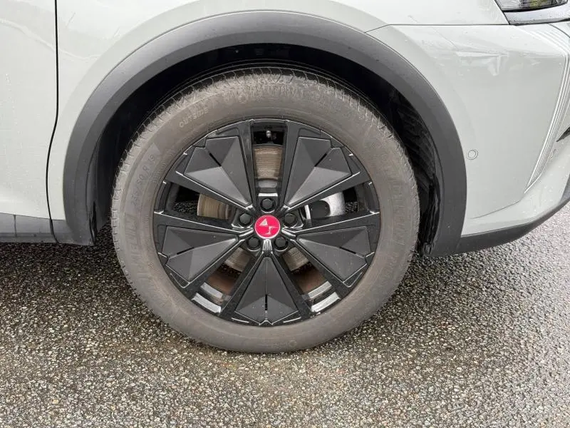 Gros plan sur la roue avant droite du DS7 E-TENSE 225ch gris 2024, avec jante noire au design géométrique distinctif.