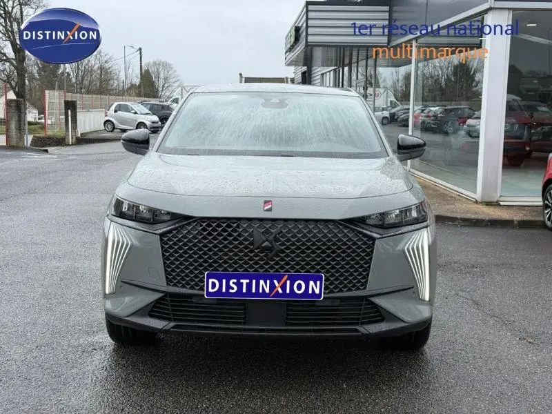 Vue frontale d'un DS7 E-TENSE gris 2024 avec calandre noire et feux LED verticaux allumés.