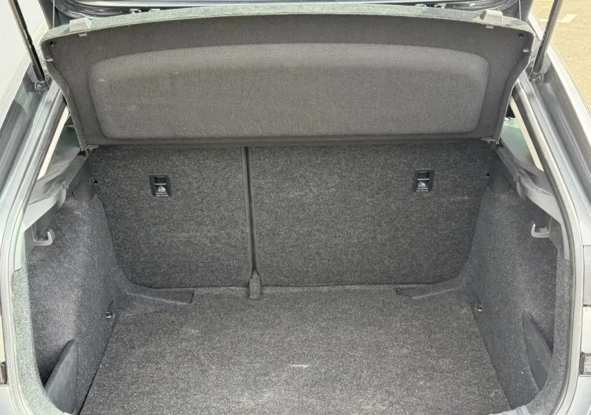 Coffre ouvert vu de l'arrière d'une Skoda Scala gris graphite, montrant l'espace de rangement intérieur.
