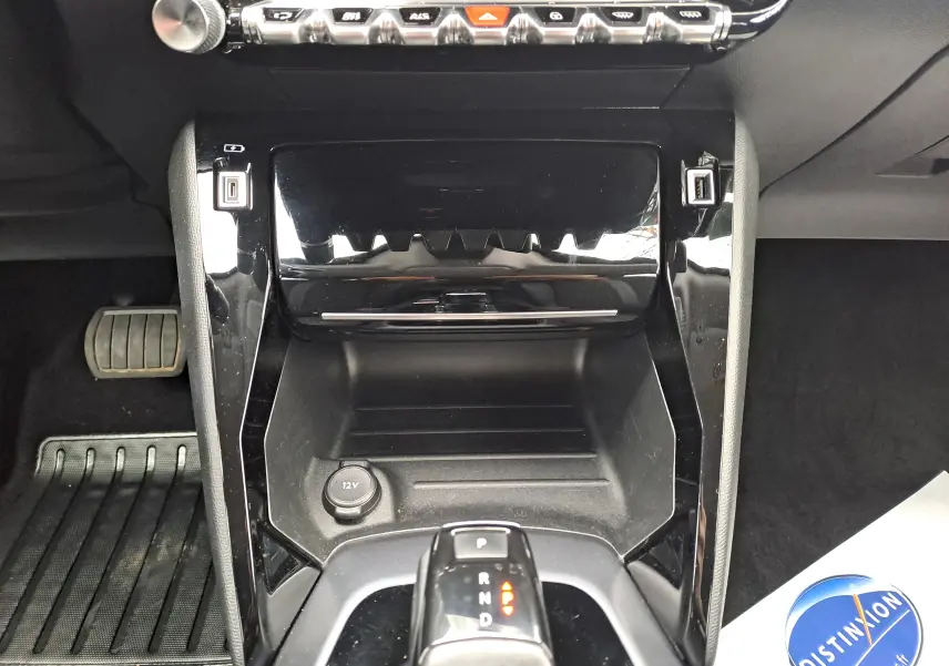 Vue rapprochée de la console centrale noire brillante du Peugeot 2008 gris Artense avec levier de boîte automatique et prises USB.