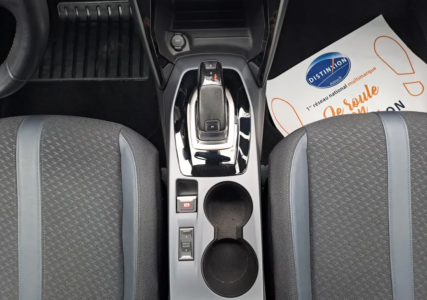 Vue plongeante sur la console centrale du Peugeot 2008 gris Artense, montrant levier de vitesse automatique et sièges tissu gris.