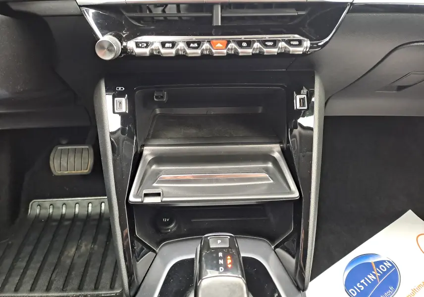 Vue rapprochée de la console centrale noire du Peugeot 2008 gris, avec levier de boîte auto et rangements ouverts.