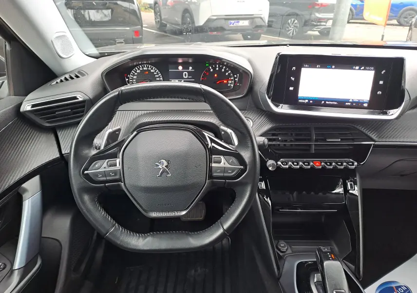 Vue intérieure frontale du tableau de bord et volant noir du Peugeot 2008 gris Artense avec écran tactile et commandes modernes.