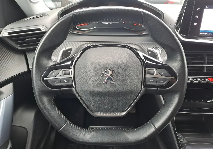 Vue rapprochée du volant cuir noir de la Peugeot 2008 2020 avec commandes intégrées et tableau de bord digital.