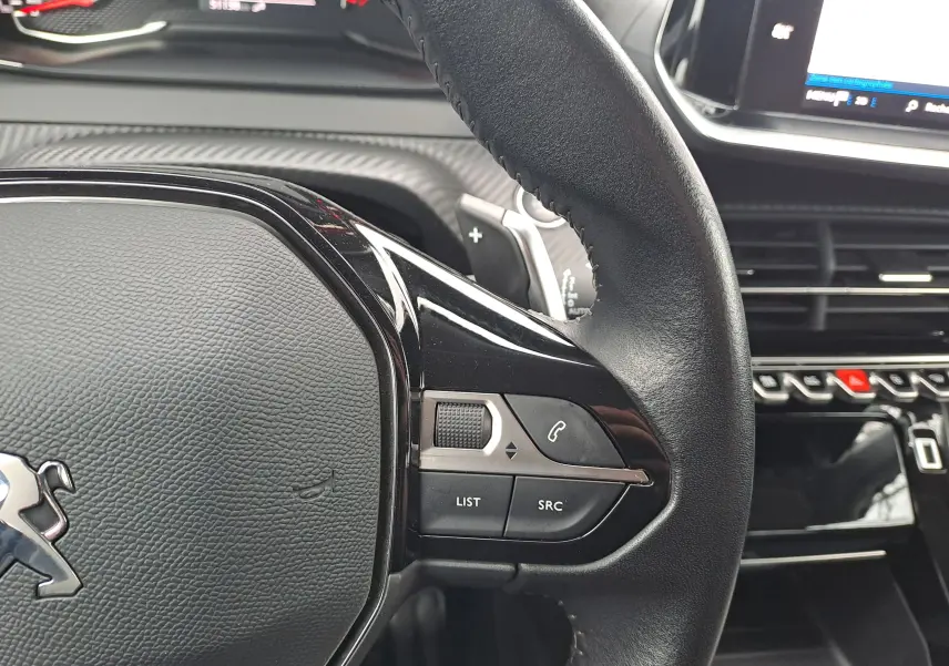 Gros plan sur le volant noir du Peugeot 2008 2020 avec commandes audio et téléphone intégrées, tableau de bord en arrière-plan.