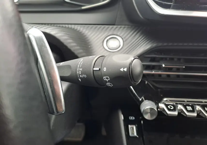 Gros plan sur la commande d’essuie-glace à gauche du volant dans l’habitacle noir du Peugeot 2008 gris Artense 2020.