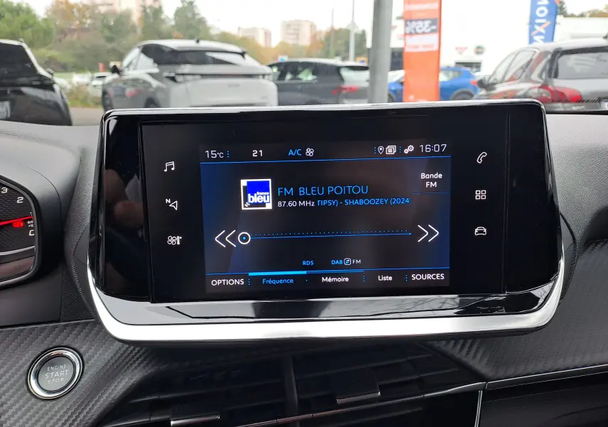 Écran tactile central allumé du Peugeot 2008 gris Artense, affichant la radio FM avec commandes tactiles autour.