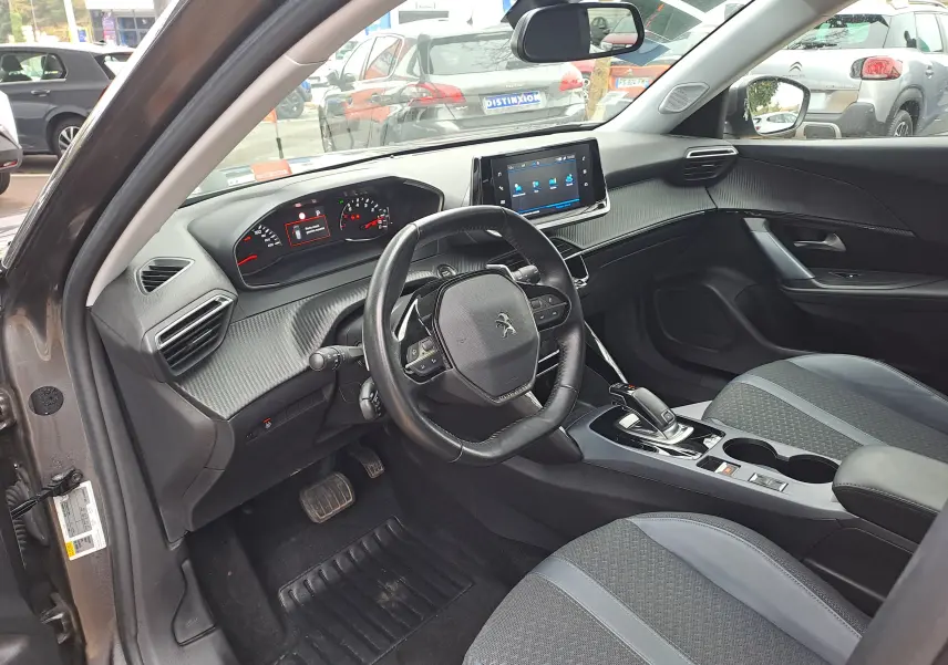 Intérieur de la Peugeot 2008 gris Artense, vue côté conducteur, tableau de bord moderne avec écran tactile et volant compact.