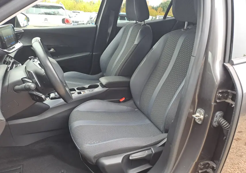Intérieur côté conducteur du Peugeot 2008 gris Artense 2020, sièges tissu gris avec surpiqûres et console centrale moderne.