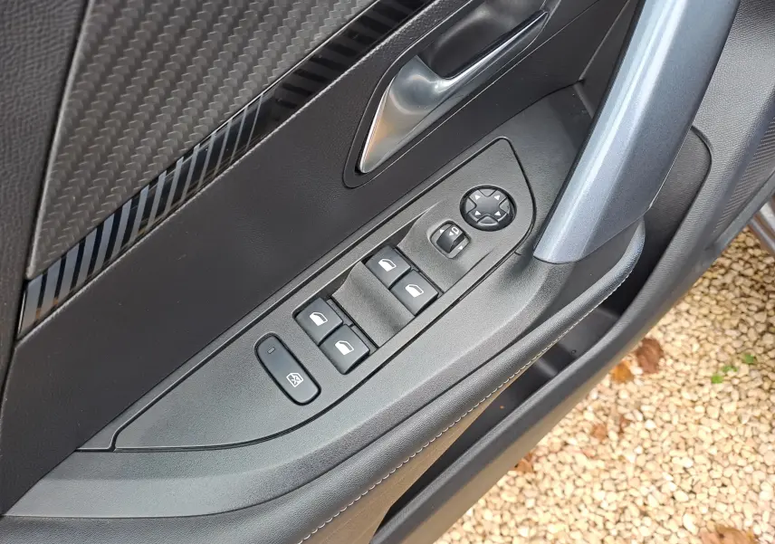 Détail de la porte côté gauche du Peugeot 2008 gris Artense 2020, avec commandes de vitres et rétroviseurs électriques.