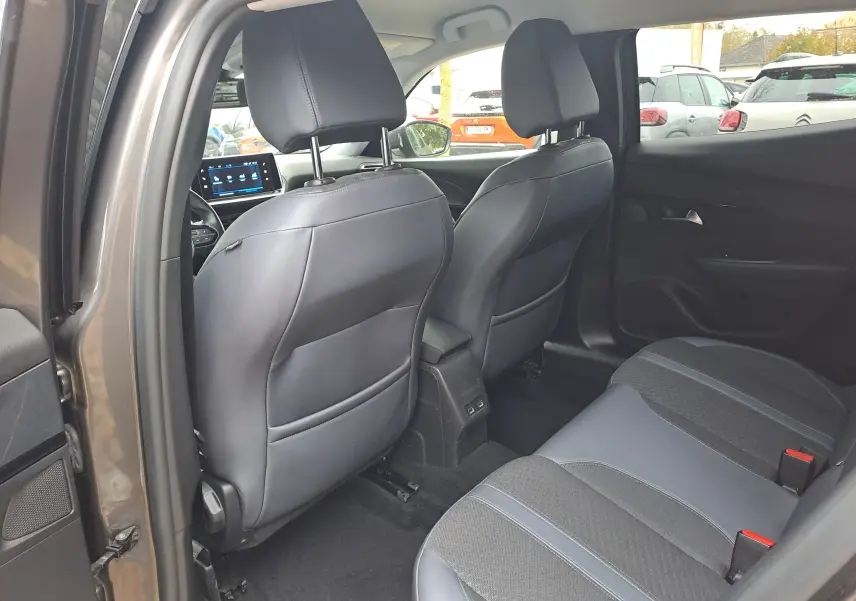 Vue intérieure arrière côté gauche du Peugeot 2008 gris Artense 2020, sièges en cuir et tissu noir, console centrale avec ports USB.