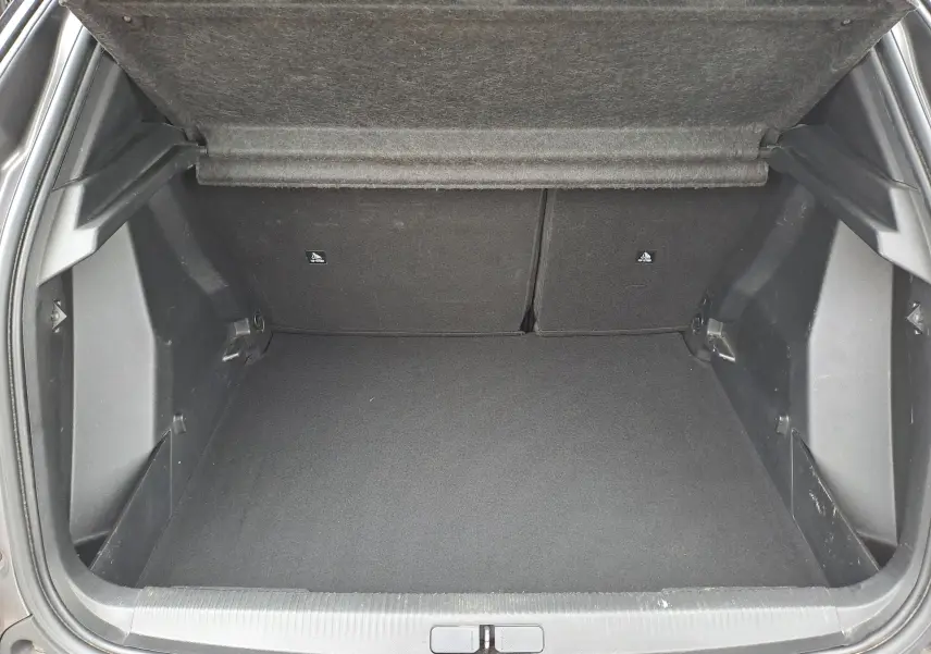 Coffre ouvert d'un Peugeot 2008 gris Artense, vue intérieure montrant l'espace de chargement vide et la tablette arrière relevée.