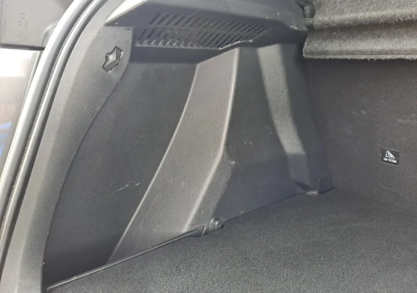 Détail de l'intérieur du coffre noir du Peugeot 2008 gris Artense, montrant la paroi latérale droite et l'attache Top Tether.