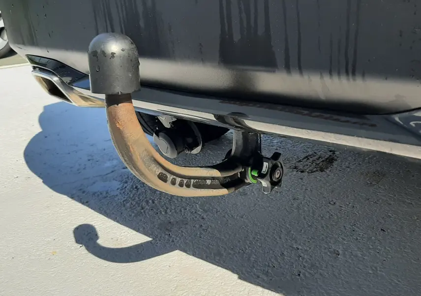 Gros plan sur l'attelage arrière rouillé d'une Peugeot 2008 gris Artense, visible sous le pare-chocs arrière.