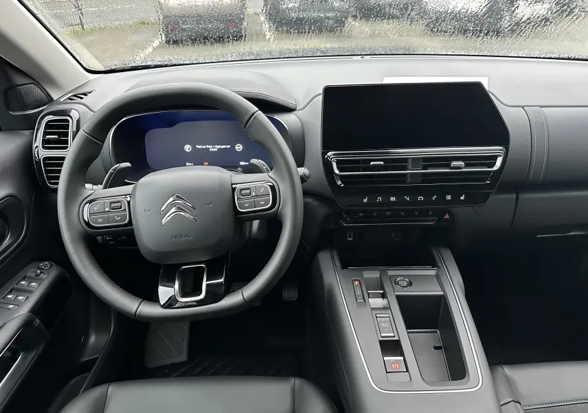 Vue intérieure du tableau de bord et volant noir du Citroën C5 Aircross 2025 avec écran tactile et commandes intégrées au volant.