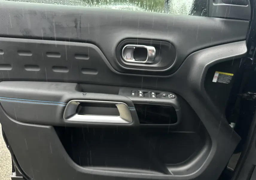 Gros plan sur la porte côté gauche du Citroën C5 Aircross Bleu Eclipse avec surpiqûres bleues et commandes électriques.