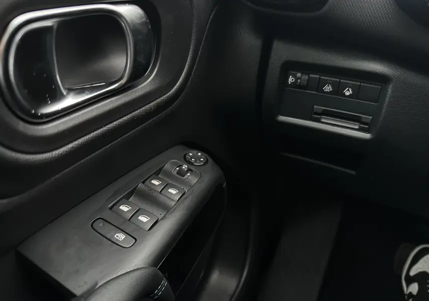Gros plan sur la commande des vitres et les boutons de réglage côté gauche intérieur noir du Citroën C5 Aircross 2025.