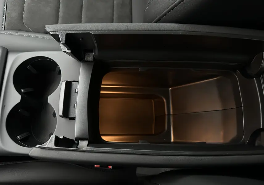 Vue plongeante sur la console centrale noire du Citroën C5 Aircross avec rangement ouvert et porte-gobelets.