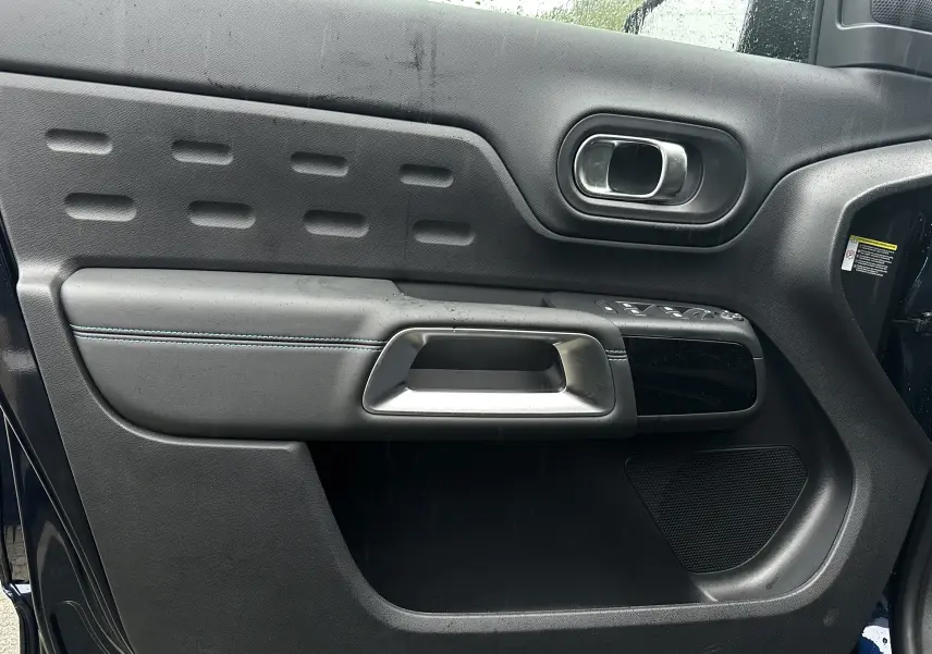 Gros plan sur la porte avant gauche du Citroën C5 Aircross Bleu Eclipse avec poignée argentée et commandes de vitres.