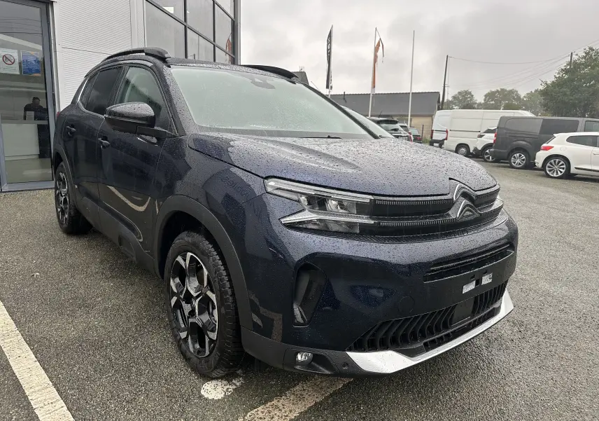Vue 3/4 avant gauche du Citroën C5 Aircross Bleu Eclipse avec jantes alliage et toit ouvrant sous la pluie.
