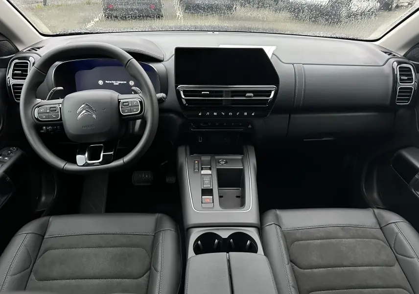 Vue intérieure avant du Citroën C5 Aircross 2025 avec tableau de bord noir, volant multifonction et sièges cuir Alcantara.