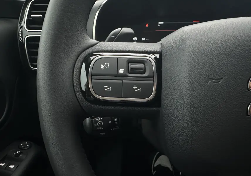 Gros plan sur le volant noir du Citroën C5 Aircross 2025 montrant les commandes de régulateur et volume à gauche.