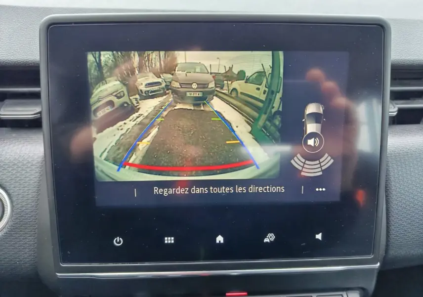 Écran tactile intérieur montrant la caméra de recul avec vue arrière et lignes de guidage colorées sur route enneigée.