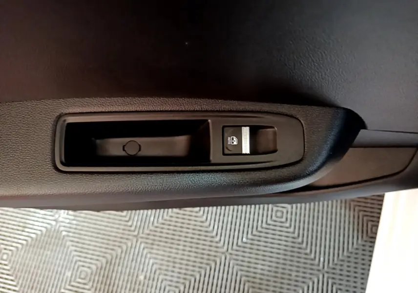 Gros plan sur le bouton de commande de la vitre électrique côté porte intérieure d’une Renault Clio Business blanche.