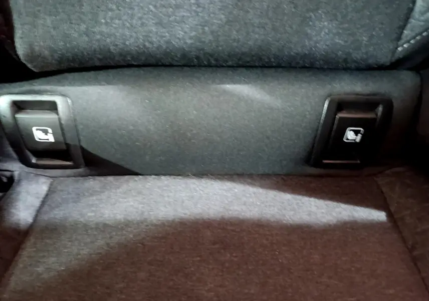 Détail des commandes de rabattement des sièges arrière sur la banquette d'une Renault Clio Business blanche.