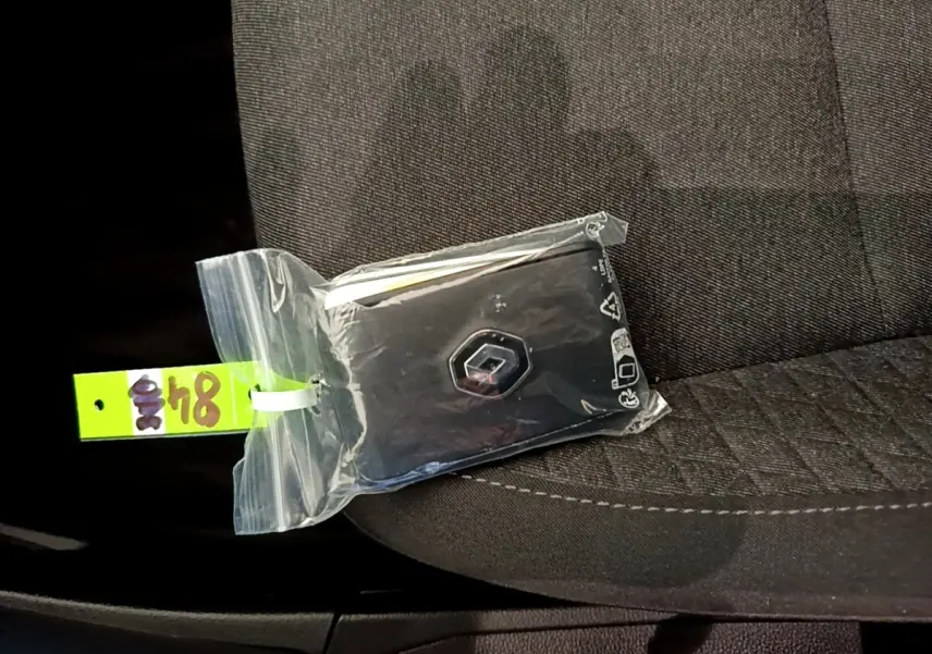 Clé Renault dans un sachet plastique posée sur un siège tissu gris foncé à l'intérieur d'une Clio blanche.