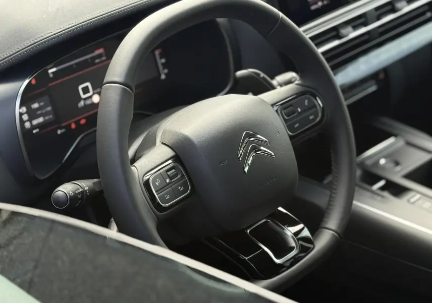 Vue rapprochée du volant cuir noir du Citroën C5 Aircross 2026 avec commandes intégrées et tableau de bord numérique.