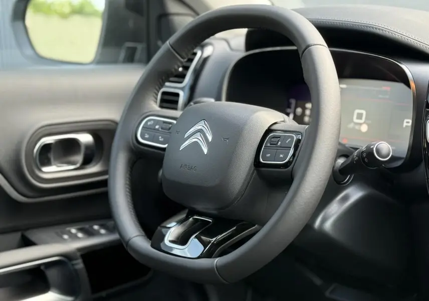 Vue rapprochée du volant cuir noir de la Citroën C5 Aircross 2026 avec commandes intégrées et tableau de bord numérique.