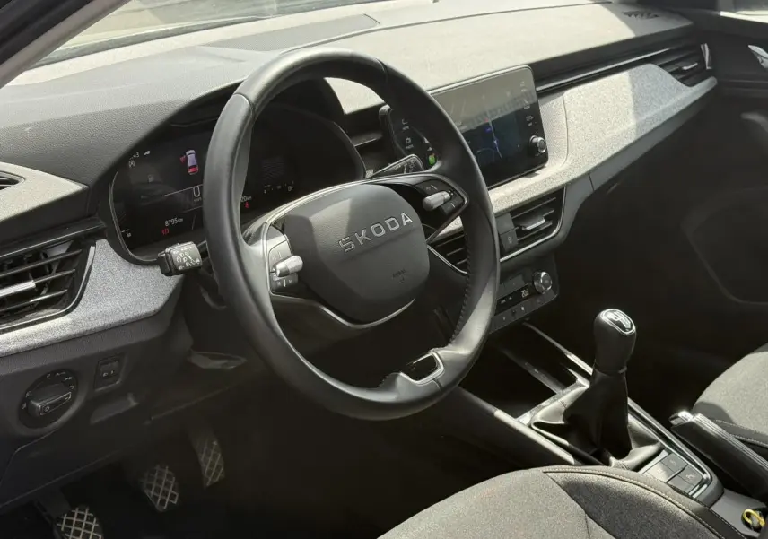 Vue intérieure côté conducteur du Skoda Scala TSI 116 gris graphite, volant cuir multifonctions et levier de vitesse manuel visibles.