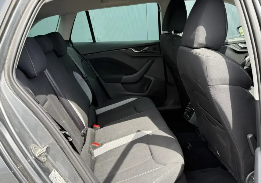 Vue intérieure arrière côté gauche de la Skoda Scala TSI 116 gris graphite, sièges tissu noir avec surpiqûres claires.