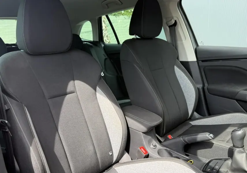 Vue intérieure des sièges avant tissu noir et gris avec accoudoir central et levier de vitesses d'une Skoda Scala TSI 116.