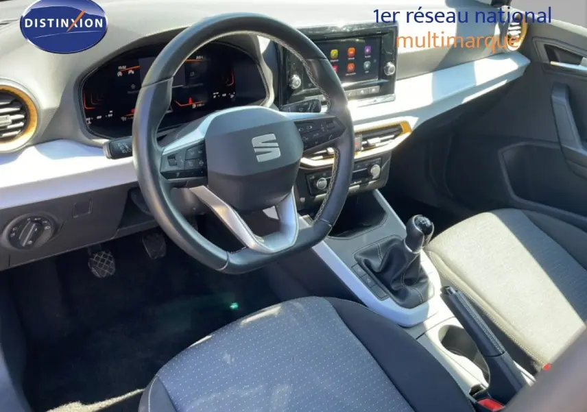 Vue intérieure du poste de conduite du SEAT Arona 2025, volant cuir multifonction et console centrale avec boîte manuelle.