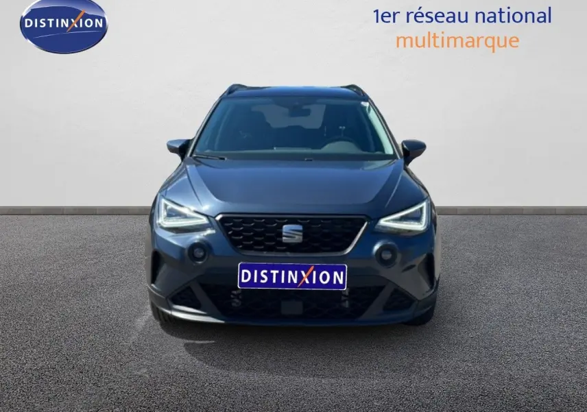Vue frontale d'un SEAT Arona gris Magnetic Metal avec toit noir, phares LED allumés sur fond neutre.